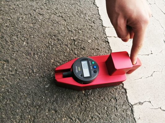 Épaisseur rouge d'inscriptions de trottoir vérifiant la pile sèche de mesure